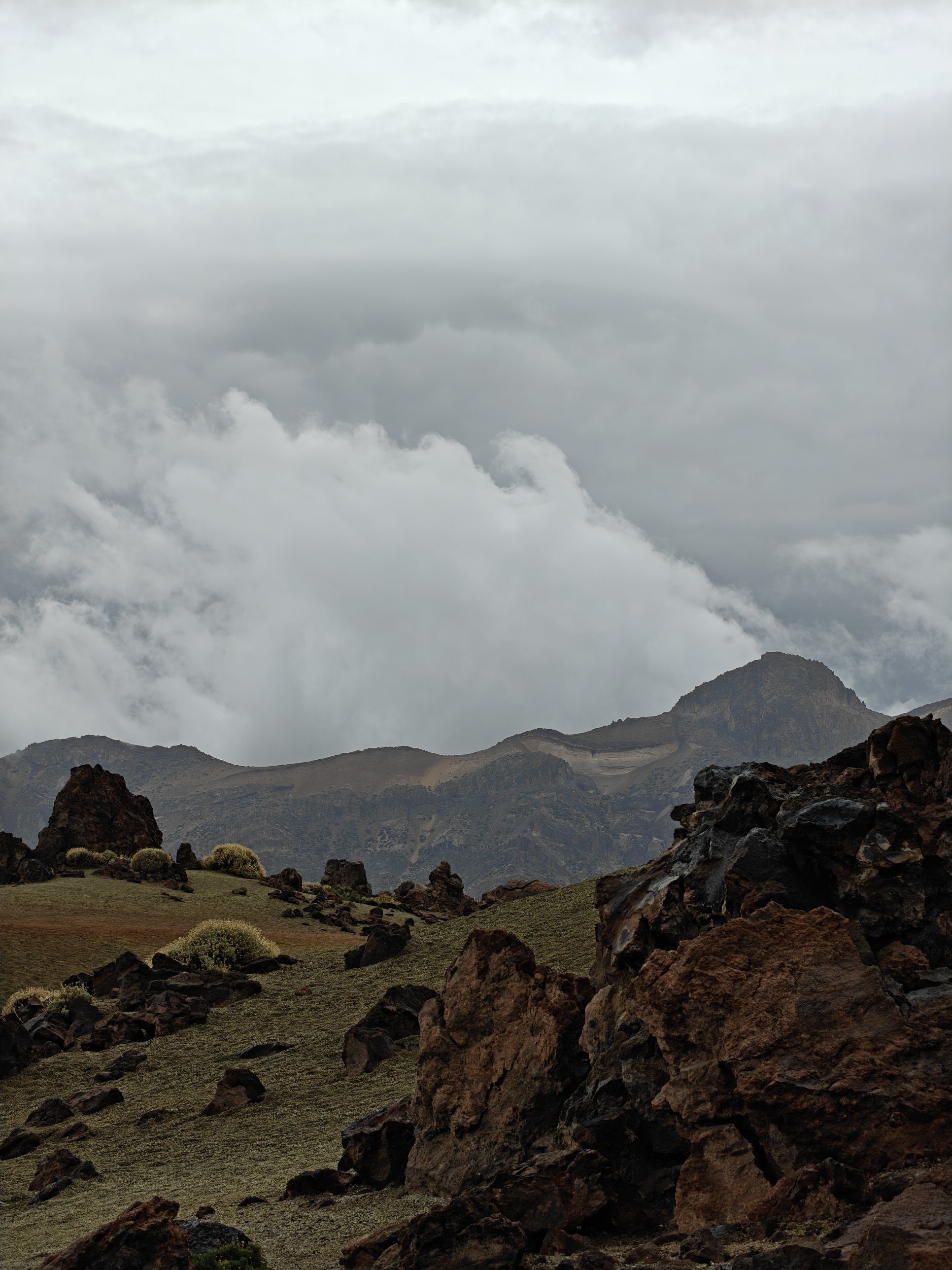 Wolken quellen über den Kraterrand bei den Minas de San José, davor rostrote Lavafelsen